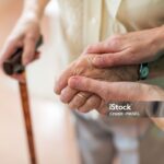 Nurse consoling her elderly patient by holding her hands