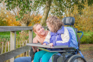 A disabled child in a wheelchair being cared for by a voluntary care worker